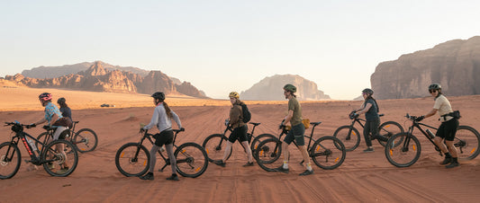A group of women walking bikes across a desert