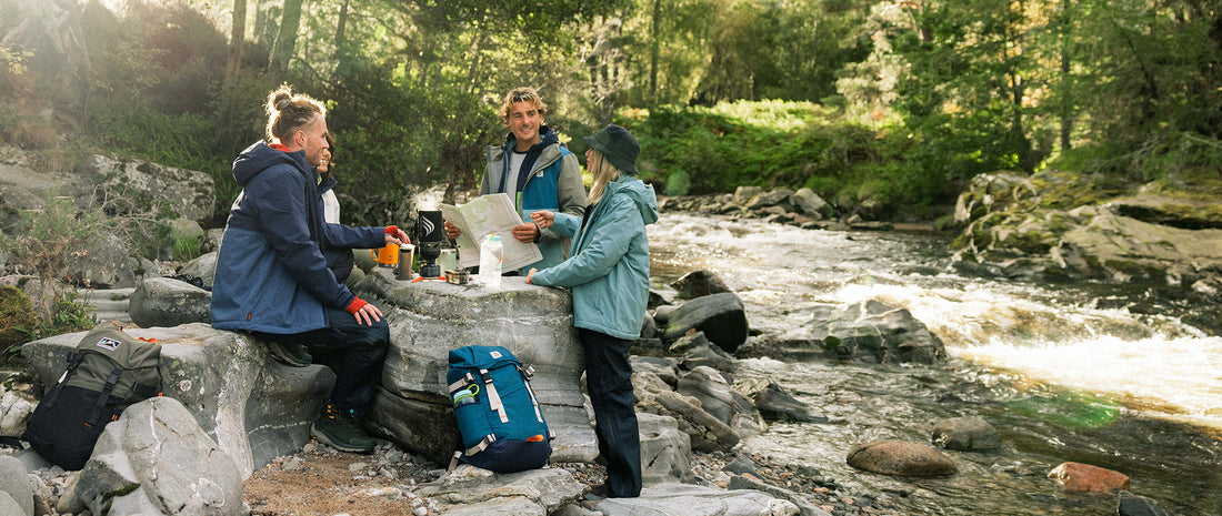 A group stood by a river, brewing coffee